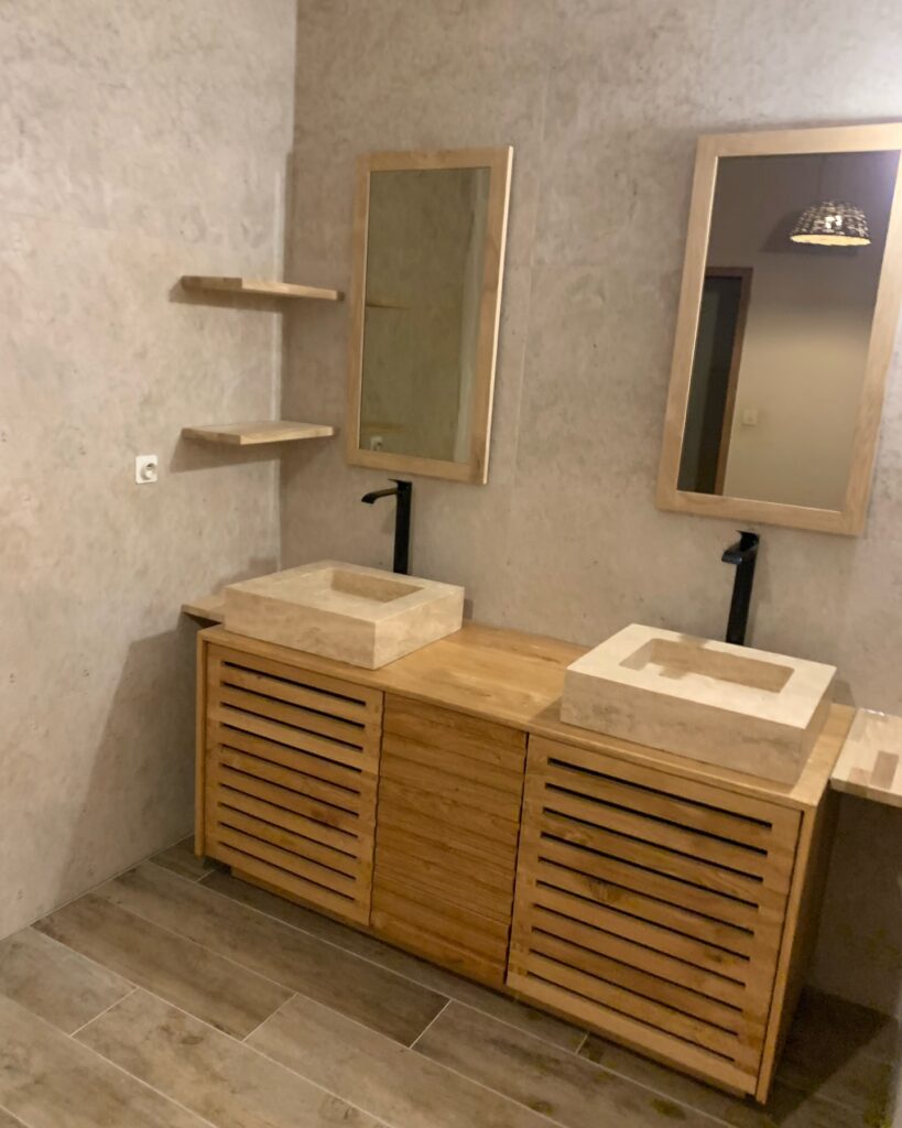 Salle de bain moderne avec meuble vasque double en bois clair, deux vasques en pierre naturelle et robinetterie noire, murs beiges.