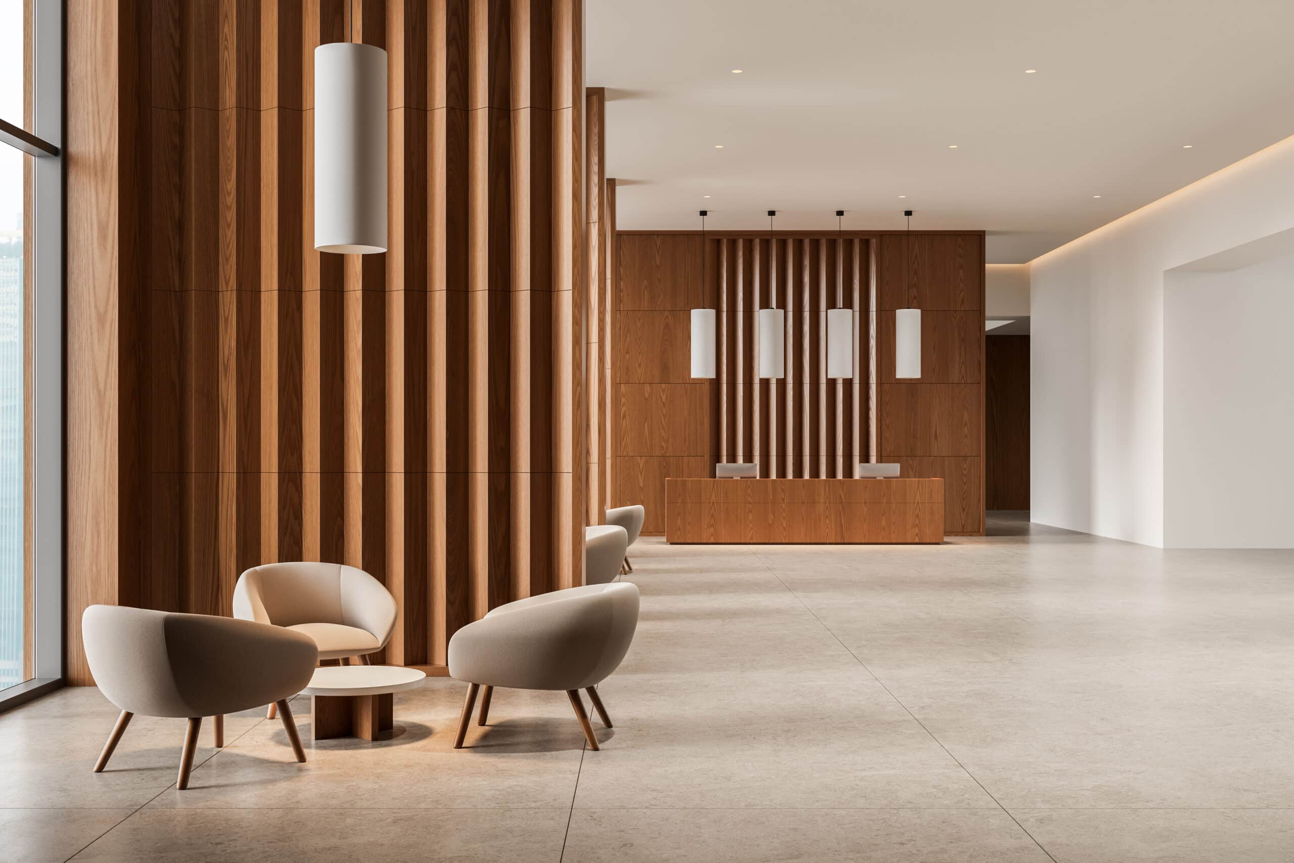 Hall d'accueil moderne avec mur en bois à lattes verticales, comptoir d'accueil en bois et fauteuils d'attente beiges près d'une fenêtre.