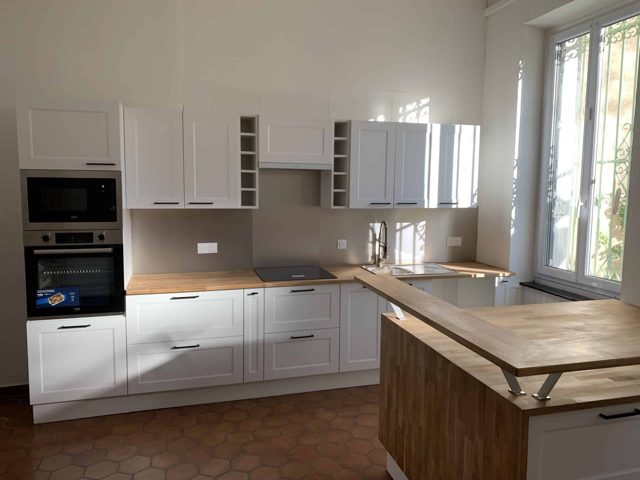 Cuisine Bois Clair et Blanc : Design Moderne Cuisine moderne et lumineuse avec armoires blanches à panneaux, plan de travail en bois clair, appareils Beko, carreaux hexagonaux terre cuite et lumière du soleil.